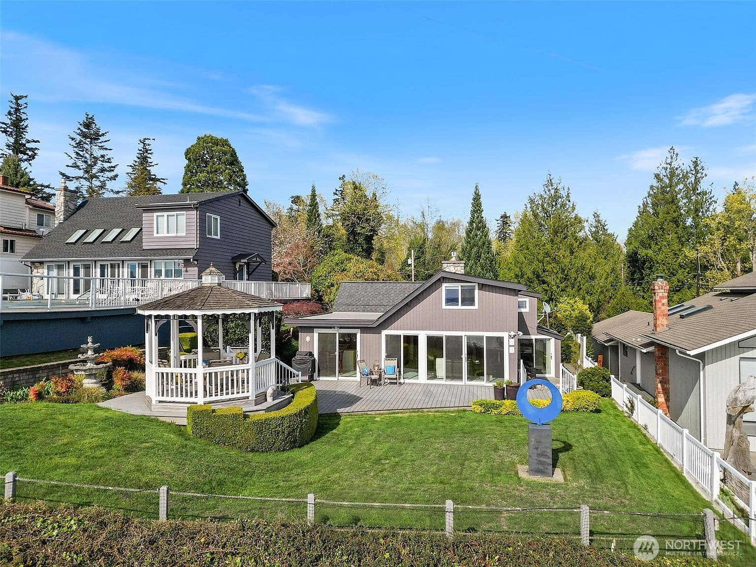 Exterior front, white home with wraparound porch and mature garden